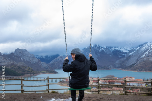 Tourist swinging over riano reservoir enjoying winter landscape, spain photo