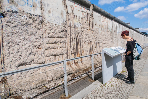 Tourist reading sign in front of berlin wall remains in germany