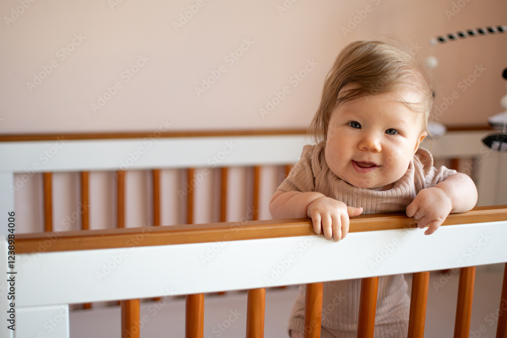 Cute Caucasian baby girl laughing standing in her crib. Portrait of laughing happy healthy 7 month old baby girl Cute Caucasian baby girl laughing standing in her crib. Portrait of laughing happy healthy 7 month old baby girl