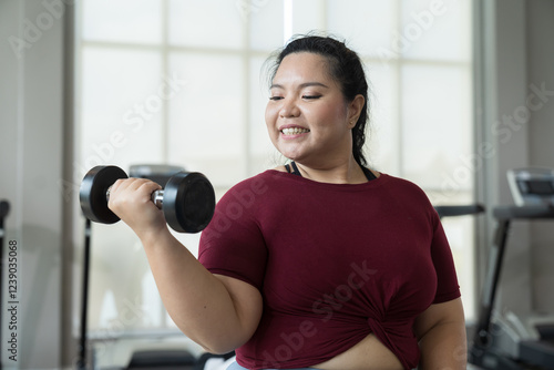 Bild auf Leinwand Happy smiling Asian young plus size woman lifting dumbbell weight in fitness club