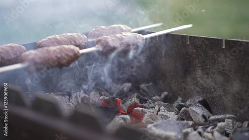 Food cooked outdoors on charcoal, hands in frame. Barbecue.