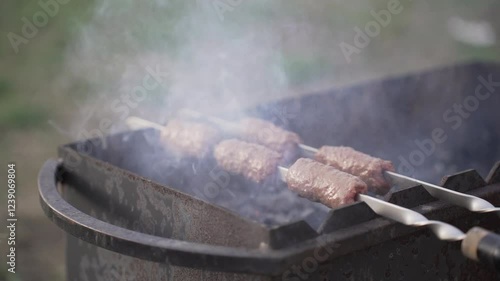 Food cooked outdoors on charcoal, hands in frame. Barbecue.
