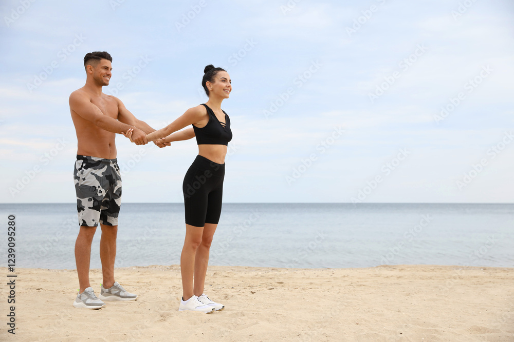 Couple doing exercise together on beach, space for text. Body training Couple doing exercise together on beach, space for text. Body training