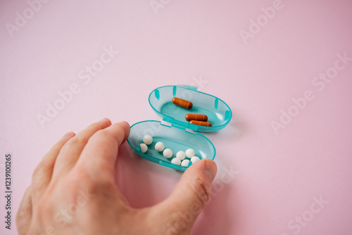 A person is grasping a container filled with various pills in their hand, which may be used for different healthrelated purposes or treatments, highlighting their importance in medicine photo