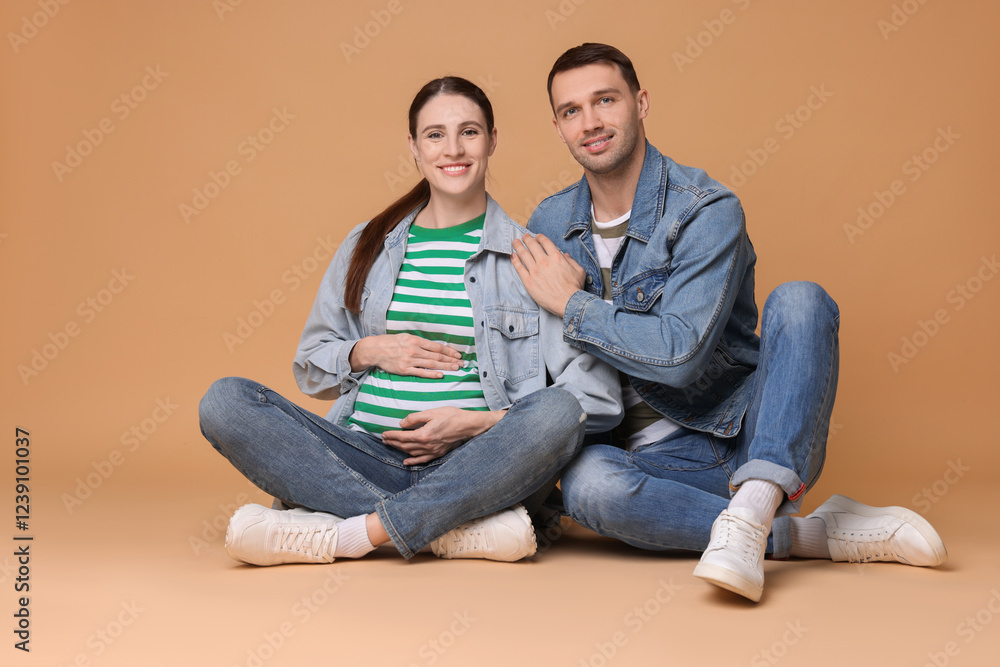 Pregnant woman and her husband on beige background Pregnant woman and her husband on beige background