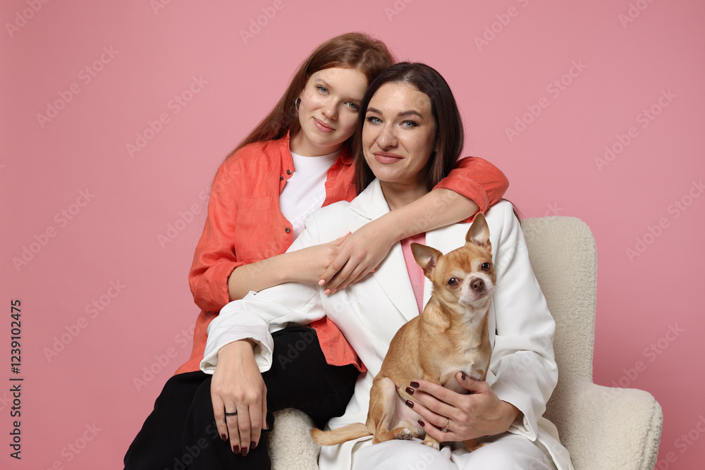 Portrait of beautiful mother with teenage daughter and cute Chihuahua dog on armchair against pink background Portrait of beautiful mother with teenage daughter and cute Chihuahua dog on armchair against pink background