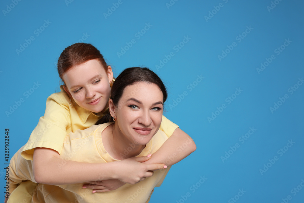 Portrait of beautiful mother with teenage daughter on light blue background, space for text Portrait of beautiful mother with teenage daughter on light blue background, space for text