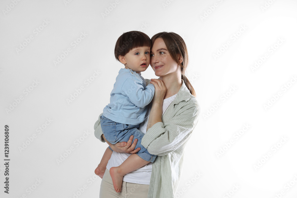 Beautiful mother with her cute little son on light grey background Beautiful mother with her cute little son on light grey background