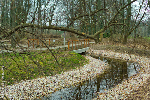 A small artificial stream with banks covered with stones in early spring in Pole Mokotowskie Park, Warsaw, Poland. photo