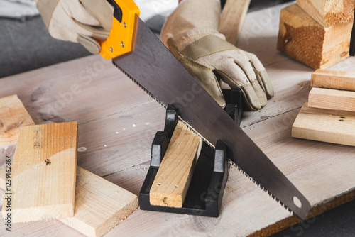 man sawing a wooden beam with a hand saw close-up