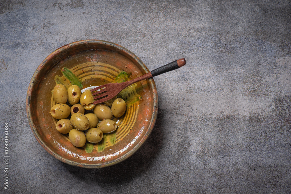 Bowl of olives with a wooden spoon on a table