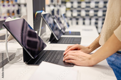 A woman is enthusiastically exploring various modern technology gadgets in an electronics store photo