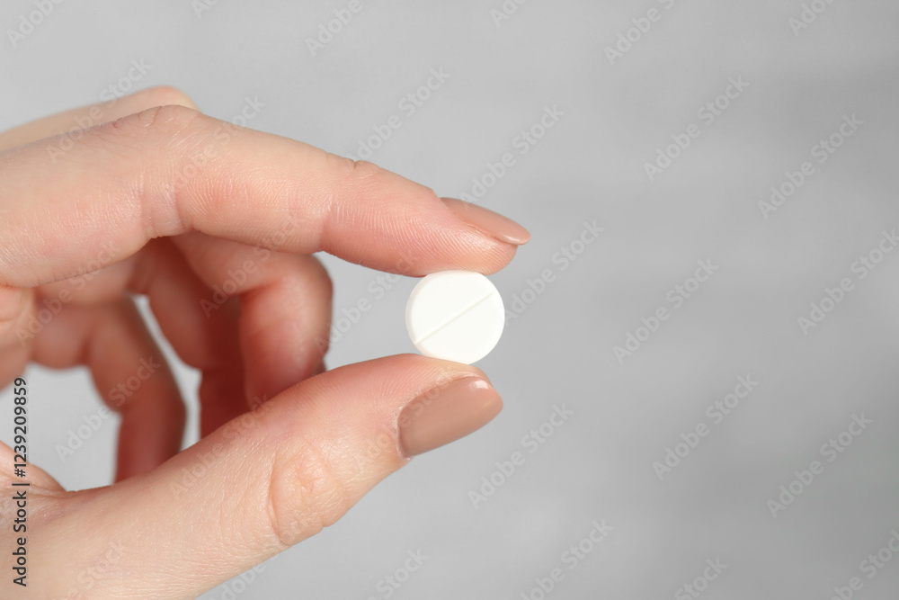 Woman holding antibiotic pill against grey background, closeup. Space for text Woman holding antibiotic pill against grey background, closeup. Space for text