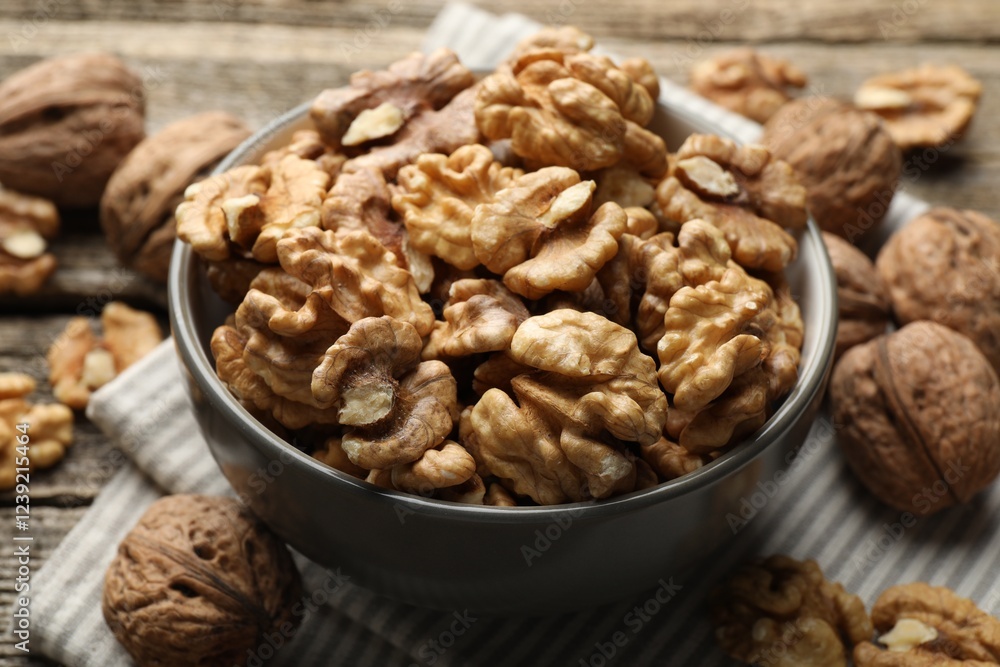Shelled walnuts in bowl and whole ones on table, closeup Shelled walnuts in bowl and whole ones on table, closeup