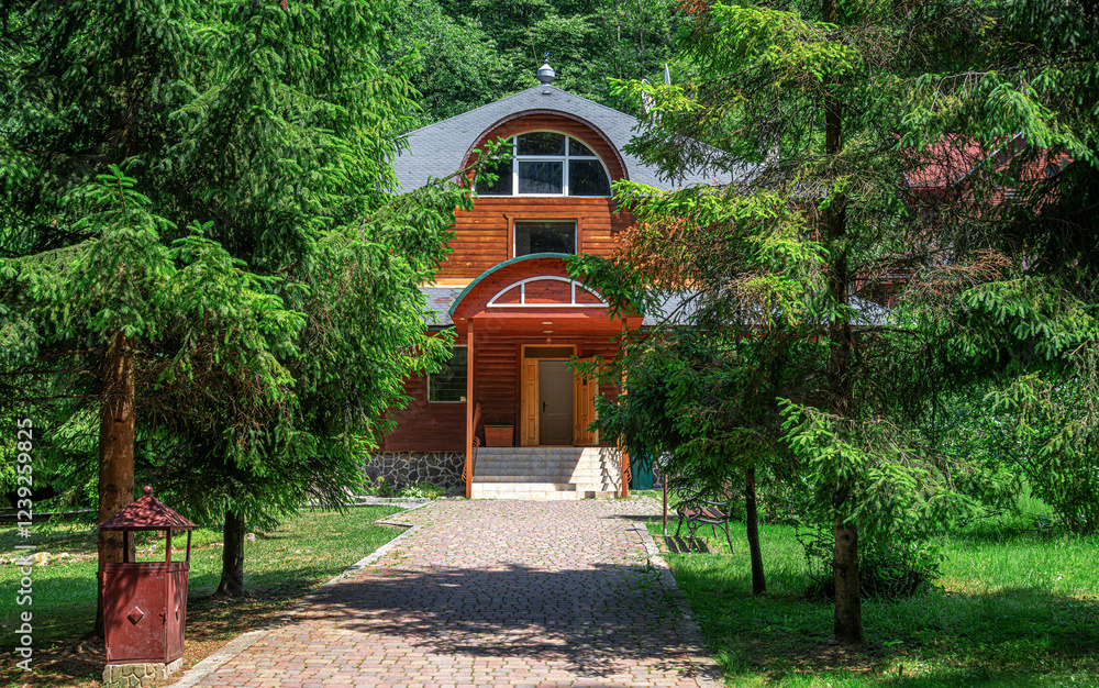 A charming wooden house is nestled among lush green pine trees, creating a peaceful and secluded atmosphere.