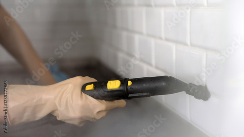Foto Housekeeper cleaning white tile grout with steam cleaner in kitchen