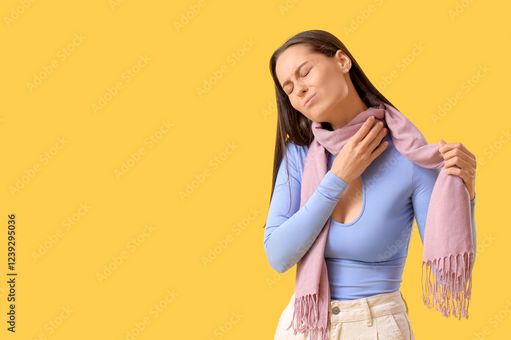 Young woman in scarf suffering from sore throat on yellow background Young woman in scarf suffering from sore throat on yellow background