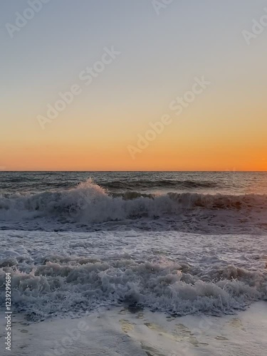 Vertical video of sea waves with foam over sunset. Summer vacation season. 