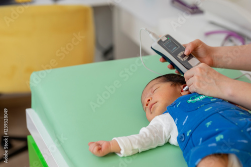 Pediatrician examining newborn baby's hearing with medical device