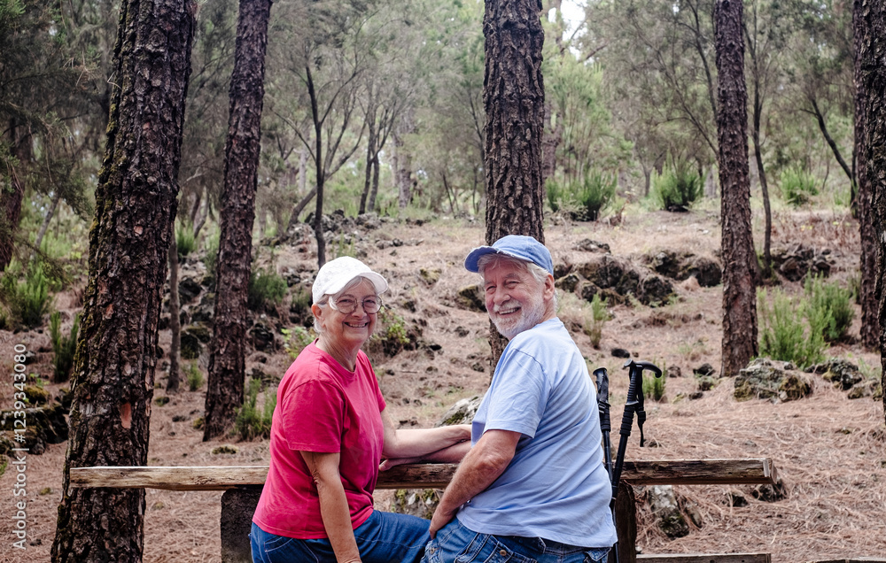 Happy senior couple sitting a a picnic table enjoying mountain day in the woods appreciating nature and freedom, retired seniors man and woman and healthy lifestyle concept Happy senior couple sitting a a picnic table enjoying mountain day in the woods appreciating nature and freedom, retired seniors man and woman and healthy lifestyle concept