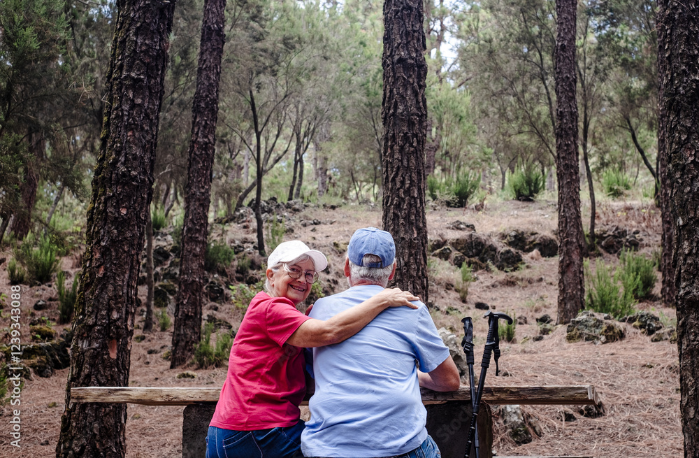Fototapeta premium Happy senior couple sitting a a picnic table enjoying mountain day in the woods appreciating nature and freedom, retired seniors man and woman and healthy lifestyle concept