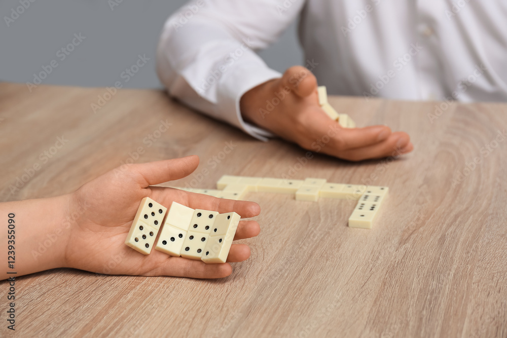Obraz premium Man and woman playing dominos on wooden table. Management concept