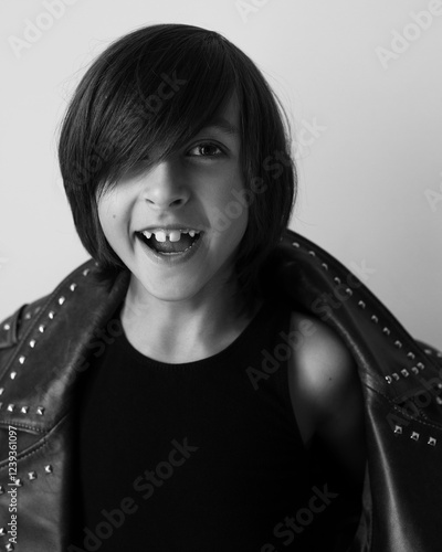 Portrait of an emotional 7-year-old boy in a large leather jacket posing in a studio. black and white photo.