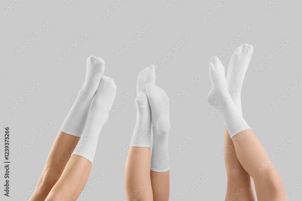 Legs of young women in white socks on grey background Legs of young women in white socks on grey background