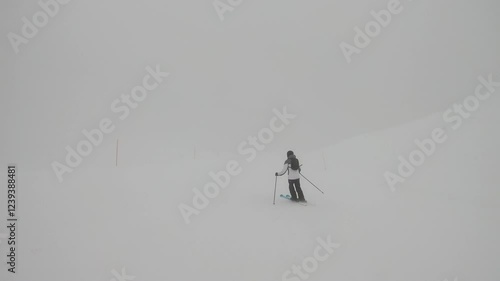 A skier navigating a thick white fog on a snow-covered path, symbolizing determination in challenging winter conditions.