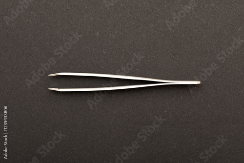 Top view extreme macro photography of white metal tweezers isolated on black background