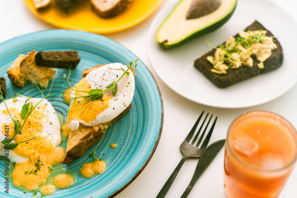 Rye bread toast with avocado and poached eggs on a blue plate on a light background. Selected focus. Keto diet, healthy dietary breakfast. Rye bread toast with avocado and poached eggs on a blue plate on a light background. Selected focus. Keto diet, healthy dietary breakfast.