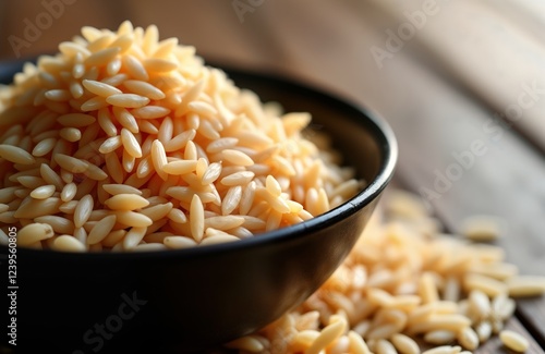 Closeup view of dark bowl filled with organic Thai highland brown rice grains. Healthy food ingredient. Raw, uncooked, unpolished grains in pile. Traditional Asian cuisine. Natural food, local photo