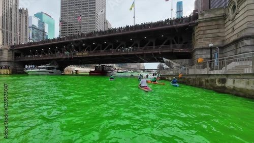 Paddle Chicago River after it was dyed green for St Patricks day with A Chicago fire boat and bridge lined with people. 