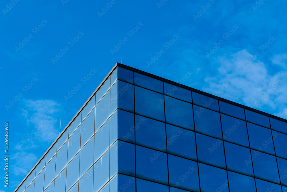Modern building with glass facade under clear blue sky Modern building with glass facade under clear blue sky