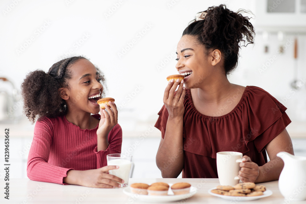 Pretty black mother and teen daughter eating cookies, happy african american girl having breakfast with her loving mom, kitchen interior. Healthy diet, calcium, vitamins in kids food concept Pretty black mother and teen daughter eating cookies, happy african american girl having breakfast with her loving mom, kitchen interior. Healthy diet, calcium, vitamins in kids food concept