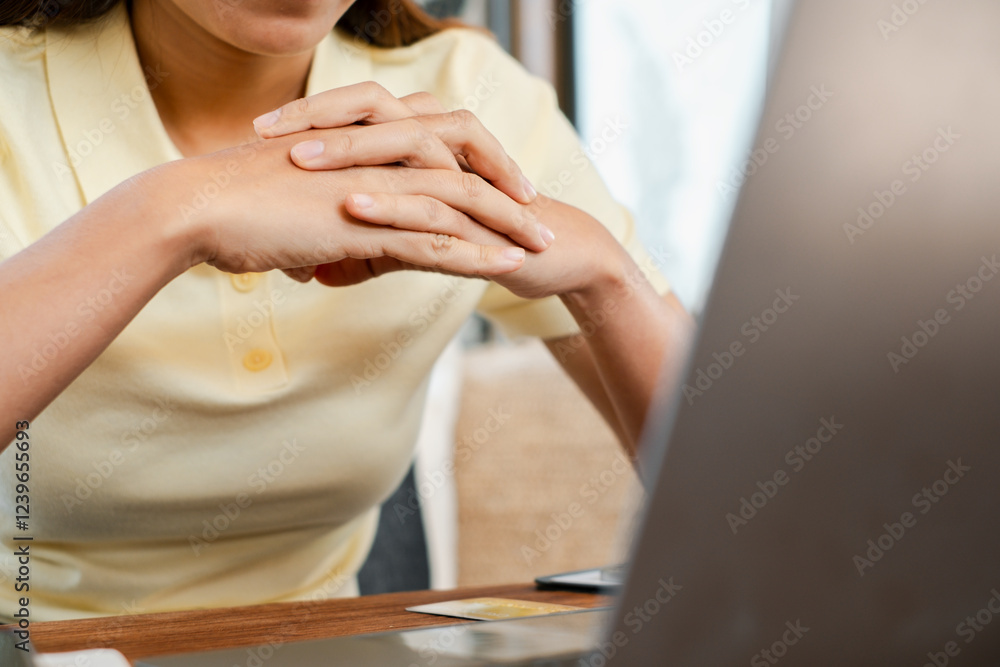 Obraz premium A woman in a yellow shirt sits thoughtfully at a desk with a laptop, creating a cozy and focused home office atmosphere.