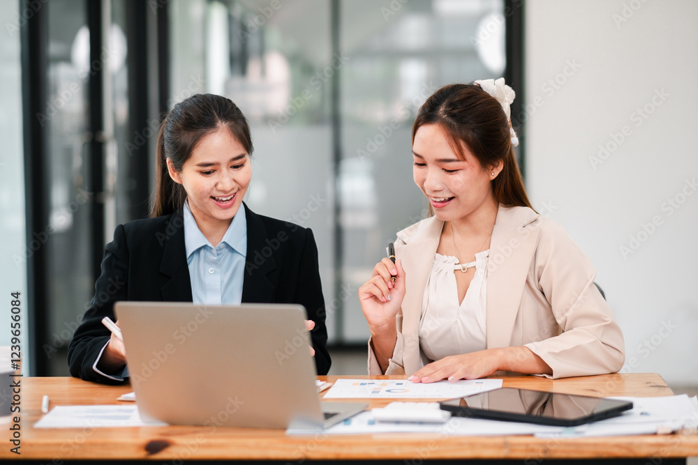 Two businesswomen working together in an office, discussing documents and using a laptop, showcasing teamwork and collaboration. Two businesswomen working together in an office, discussing documents and using a laptop, showcasing teamwork and collaboration.