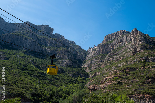 A yellow cable car glides up Montserrat's majestic mountainside, offering breathtaking views of the Spanish landscape.