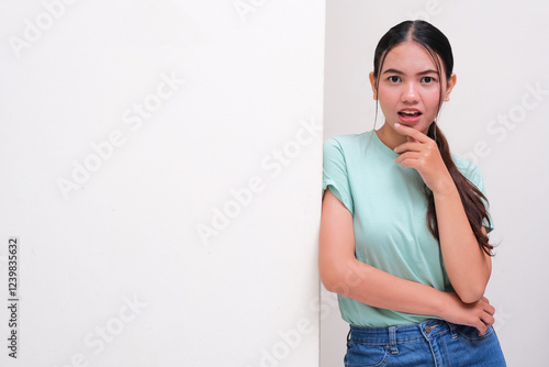 A woman leaning on the wall showing shocked face expression photo