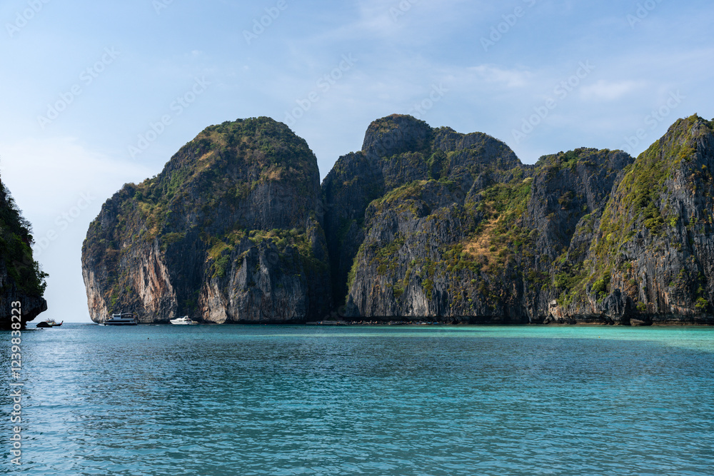 Naklejka premium Serene tropical bay with dramatic cliffs and turquoise water, perfect for a relaxing getaway.