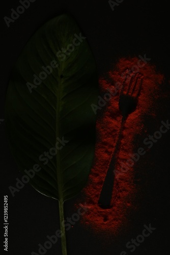 Conceptual image of condiments and kitchen fork with tropical green leaf, a harmonious combination of nature and gastronomy