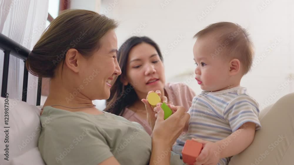 Asian lesbian couple lovingly caring for and raising their baby boy at home. Asian lesbian couple lovingly caring for and raising their baby boy at home.