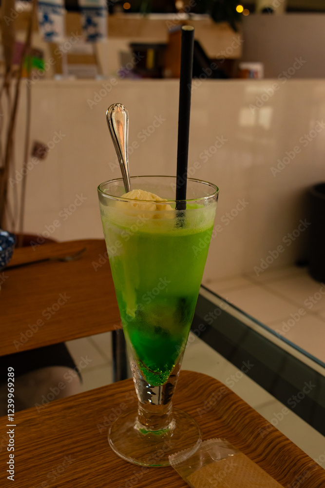 This beautiful green drink looks really refreshing. This is a melon soda float served in Japan. A straw sits in by a scoop of vanilla ice cream and a spoon. This is also known as cream soda. This beautiful green drink looks really refreshing. This is a melon soda float served in Japan. A straw sits in by a scoop of vanilla ice cream and a spoon. This is also known as cream soda.
