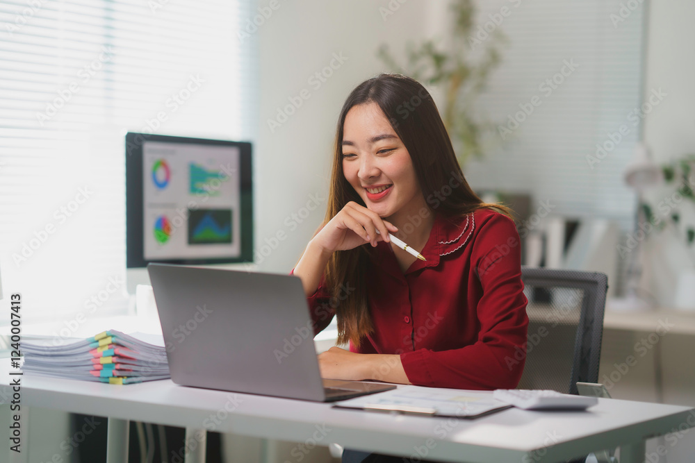 Asian businesswoman smiling and working using laptop at the office Asian businesswoman smiling and working using laptop at the office