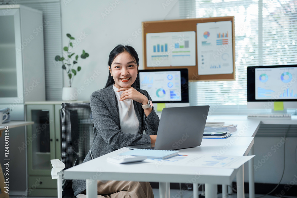 Asian businesswoman smiling and working using laptop computer in modern office Asian businesswoman smiling and working using laptop computer in modern office