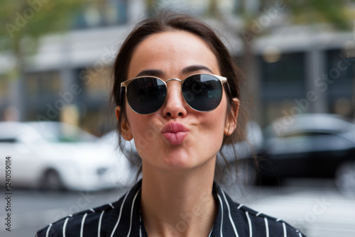 Stylish woman wearing sunglasses puckering lips
