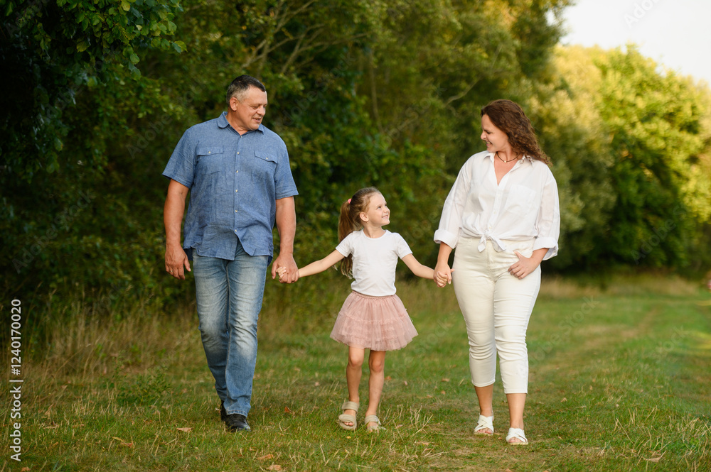 Family spending time together in summer. Mom, dad, girl walking along park path among trees, holding hands, smiling happily, looking at each other. Family, love and parenthood concept, happy childhood Family spending time together in summer. Mom, dad, girl walking along park path among trees, holding hands, smiling happily, looking at each other. Family, love and parenthood concept, happy childhood