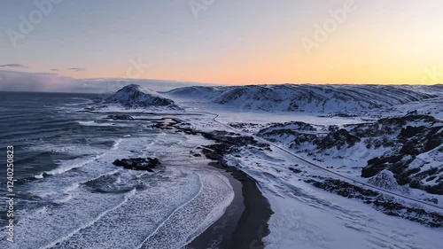 Wallpaper Mural Aerial drone footage gliding and flying over winter white snow covered Norway beach shoreline with mountains in the background during sunset or sunrise what is vibrant orange colored. road visible. Torontodigital.ca