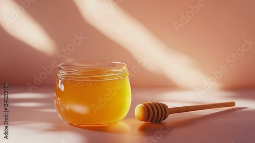 Honey in a jar with a wooden dipper surrounded by fresh green leaves on a bri...