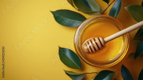 Honey in a jar with a wooden dipper surrounded by fresh green leaves on a bri...